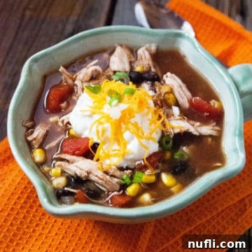 Crockpot Chicken Enchilada Soup in a bowl on a orange cloth napkin next to a spoon