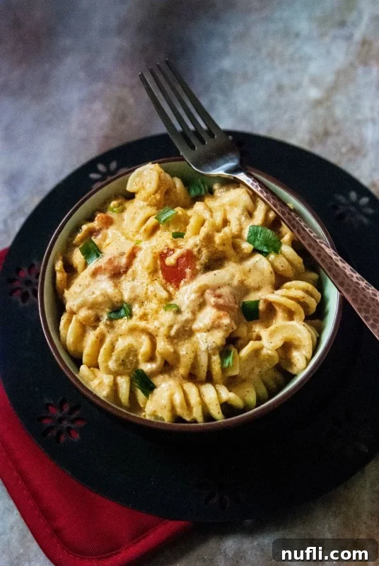 Fiesta Slow Cooker Mac and Cheese 2 A bowl of creamy Mexican mac and cheese, garnished with fresh cilantro, on a wooden table.