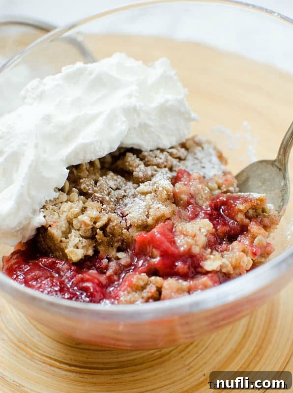 strawberry crisp with whipped cream in a bowl with a spoon 