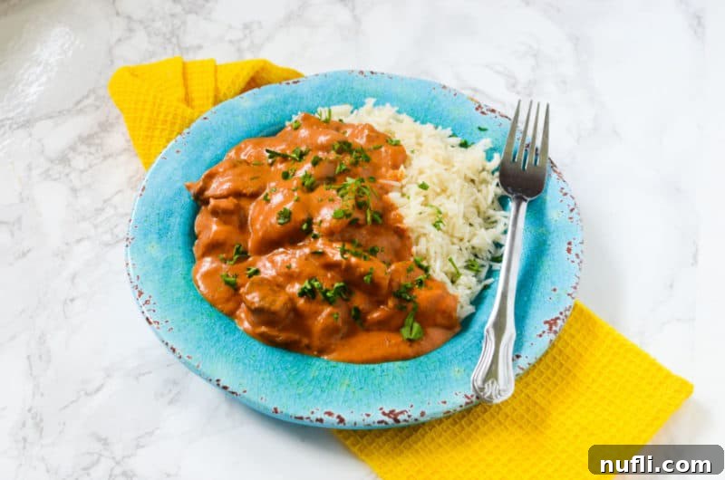  blue plate with chicken tikka masala, white rice, and a fork