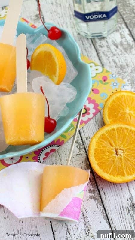 Vodka bottle next to a blue bowl filled with popsicles, ice, lime wedges, and maraschino cherries