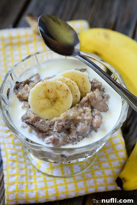 Close-up of Slow Cooker Banana Bread Oatmeal in a glass bowl with sliced bananas and a spoon, highlighting the creamy texture and inviting presentation.