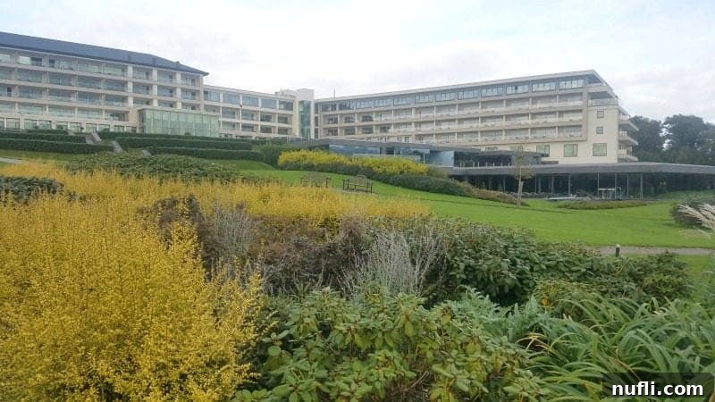 Lakeside Elegance in Killarney: The Europe Hotel 7 The grand exterior of The Europe Hotel Killarney, majestically situated amidst rolling green hills and lush vegetation.