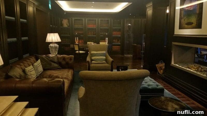 Lakeside Elegance in Killarney: The Europe Hotel 9 Elegant library room at The Europe Hotel Killarney, featuring dark wood paneling, extensive bookshelves, and plush seating by a cozy fireplace.