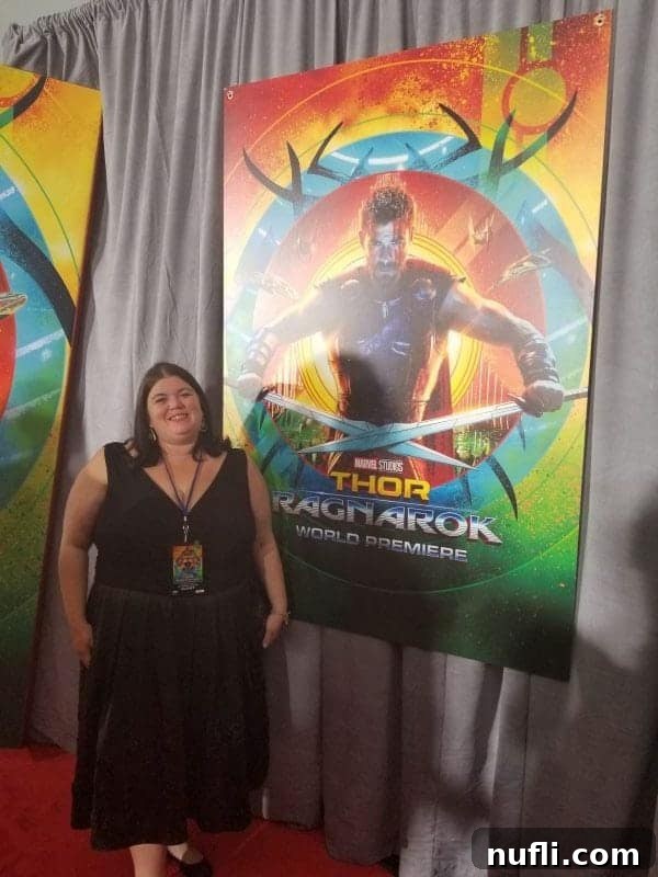 Tammilee standing next to a Thor Ragnarok world premiere poster, smiling brightly