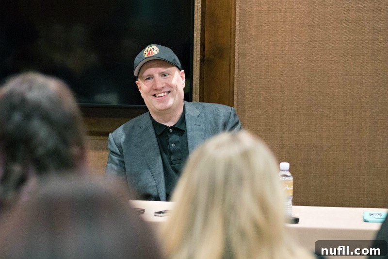 Kevin Feige is shown sitting at a table, smiling warmly, reflecting on Marvel's achievements.