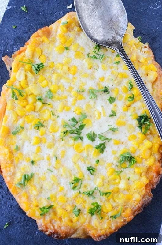 Close up of Crockpot Corn Pudding with a spoon over it