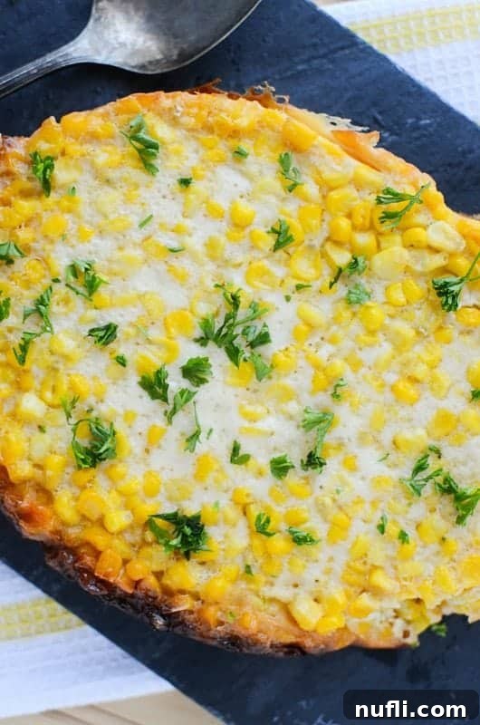 Crockpot Corn Pudding with a green garnish on a dark background with a silver spoon. 