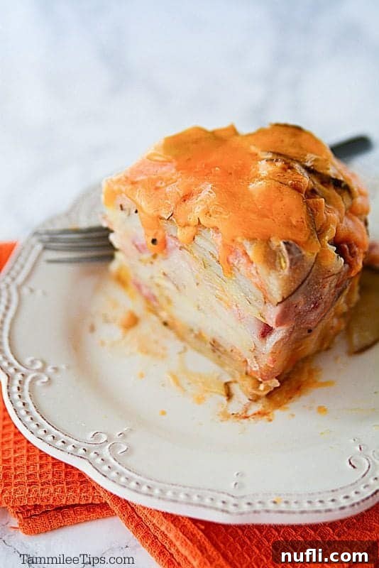scalloped potatoes and ham on a white plate with a fork