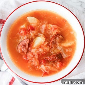 Sausage Sauerkraut Soup in a white bowl on a cloth napkin