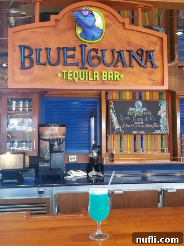 Vibrant Blue Margarita 4 Blue margarita in a cocktail glass below a Blue Iguana Tequila Bar Sign