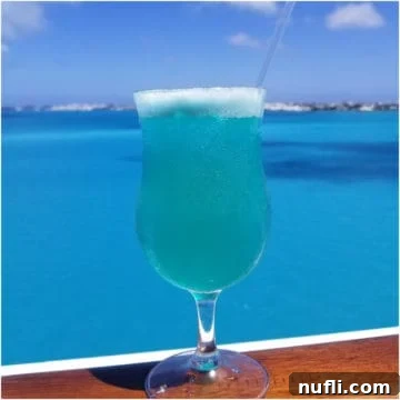 Vibrant Blue Margarita 7 Blue Margarita on a wood rail with the ocean behind it