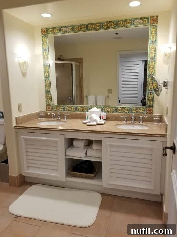 bathroom with two sinks, cabinet with towels and a large mirror
