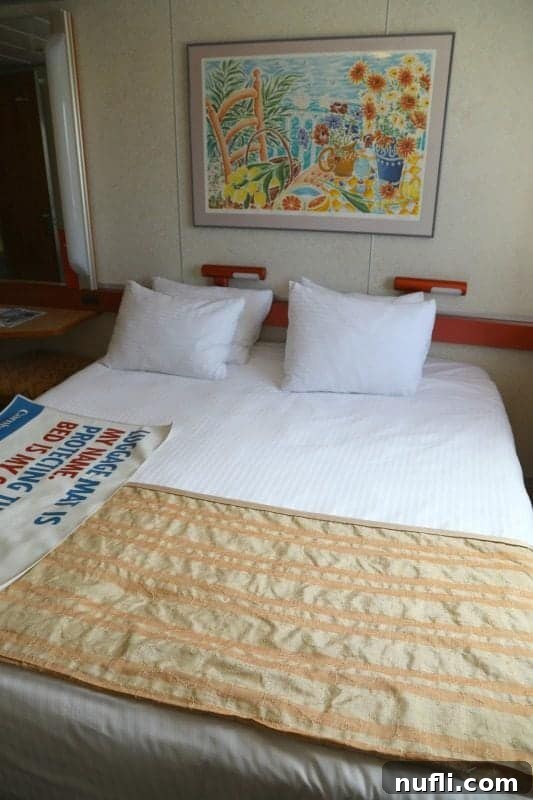 Comfortable stateroom bed with decorative artwork above on Carnival Imagination.