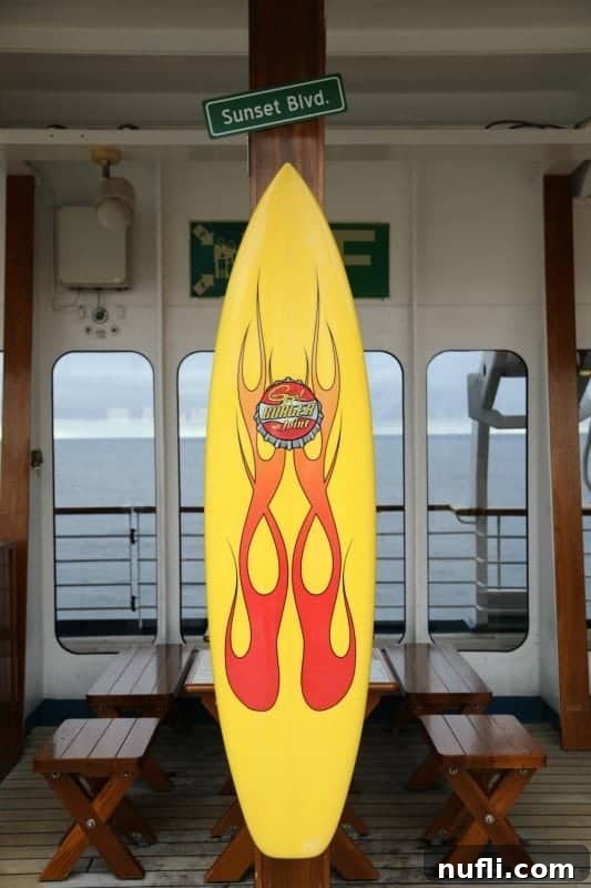 A yellow surfboard decorated with the logo for Guy's Burger Joint, a popular eatery on Carnival cruises.