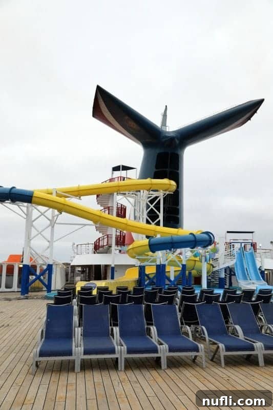 A view of Carnival Imagination's aft deck, featuring waterslides and sun loungers.