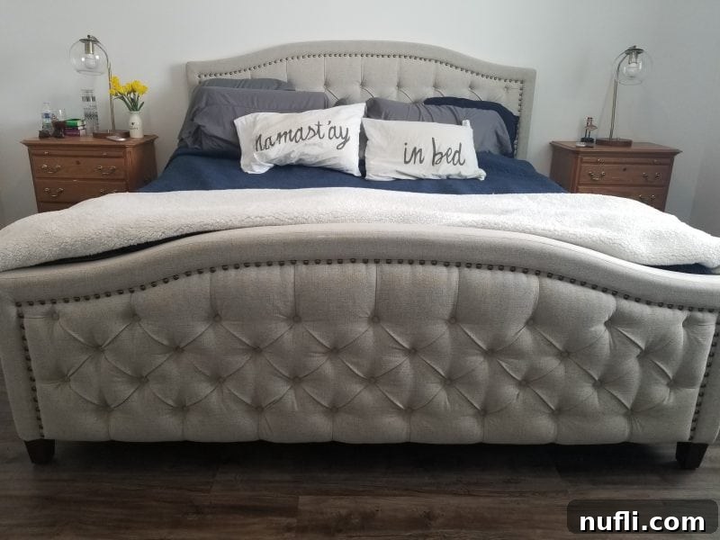 Bed made with comforters next to two nightstands with flower's and lamps on them. 