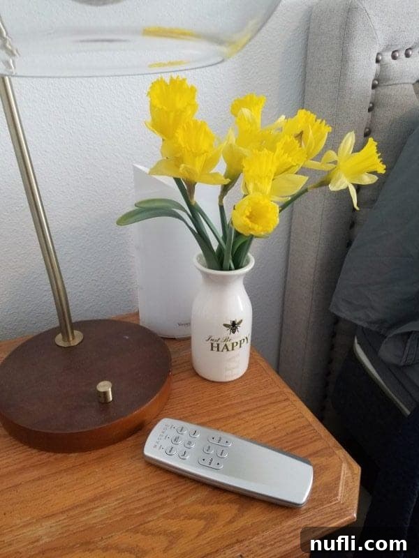 LulaaBed remote next to a vase of daffodils and a lamp on a nighstand