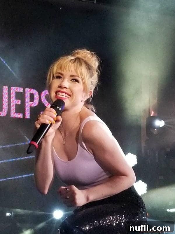 Carly Rae Jepsen, pop music sensation, holding a microphone and smiling warmly during her dynamic performance.