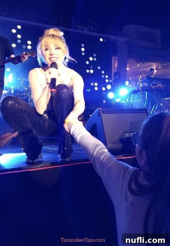 Carly Rae Jepsen kindly holding a young girl's hand during her performance, demonstrating a personal connection with her fans.