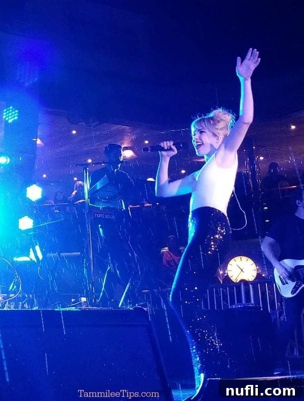 Carly Rae Jepsen singing live on stage, energized by performing in the rain, a memorable moment during her Carnival Splendor concert.
