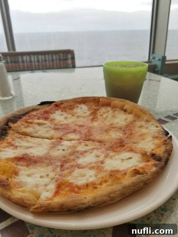 A tempting cheese pizza on a table, perfectly positioned for a meal with a beautiful ocean view from the Carnival Splendor.