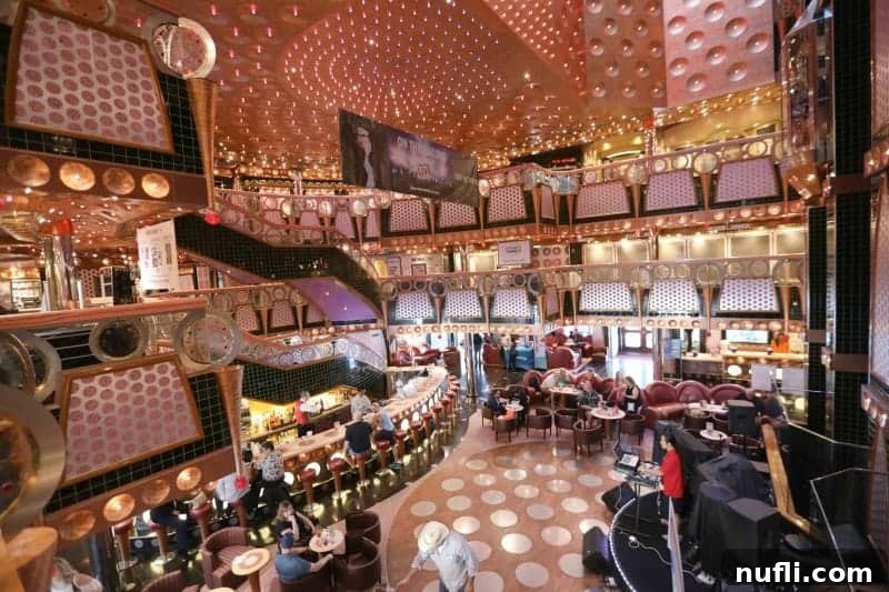 The impressive Carnival Splendor lobby, spanning multiple levels, with guests enjoying drinks at the lively bar.