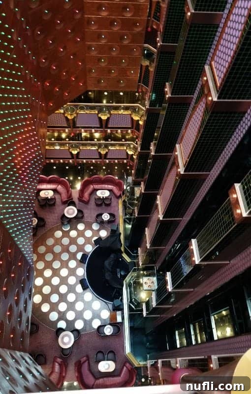 A stunning perspective looking down through multiple floors of the Carnival Splendor's atrium, revealing the stage below and elevators lining the sides.