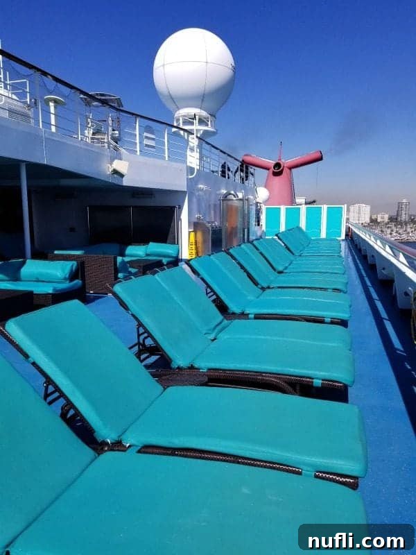 Relaxing serenity deck chairs lined up with the iconic Carnival Splendor funnel prominently in the background, creating a picturesque scene.