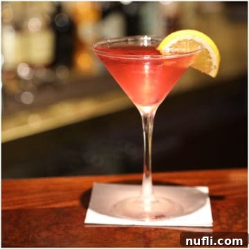 Golden Hour Island Martini 7 Red martini with a lemon wedge in a martini glass