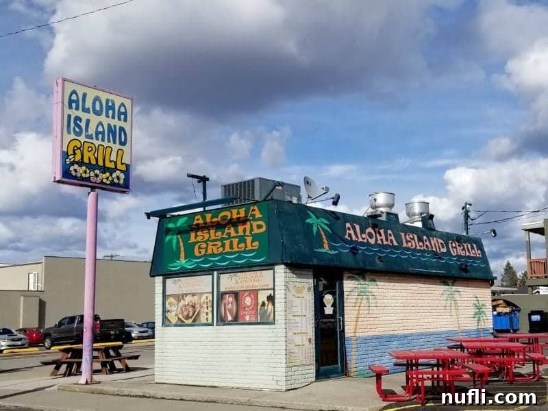 Aloha Island Grill sign next to a building with red picnic tables
