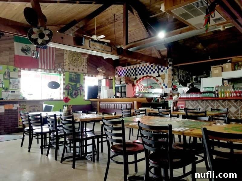Tables and chairs near a Mexican Flag and restaurant signs