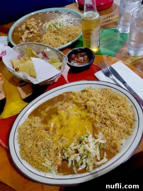 Cheese enchiladas with rice next to chips and salsa and a drink