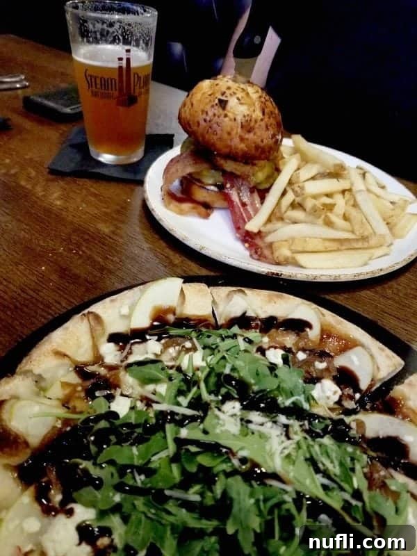 pizza on a plate next to a burger and beer