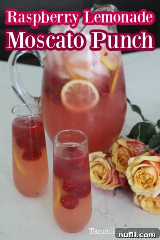 A sparkling Raspberry Lemonade Moscato Punch served in a glass pitcher, garnished with fresh raspberries and lemon slices, surrounded by elegant roses and individual glasses ready for enjoyment.