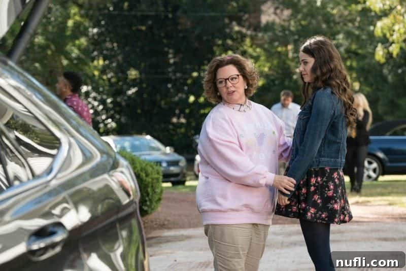 Melissa McCarthy's character in 'Life of the Party' confidently standing next to a car, a memorable scene from the movie.