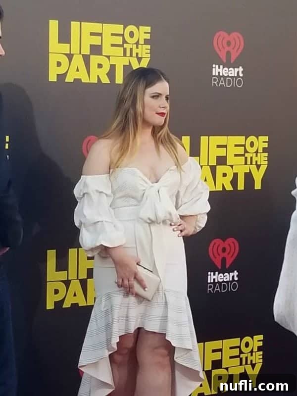 Jessie Ennis standing confidently beside a 'Life of the Party' premiere sign, engaging with the event's excitement.