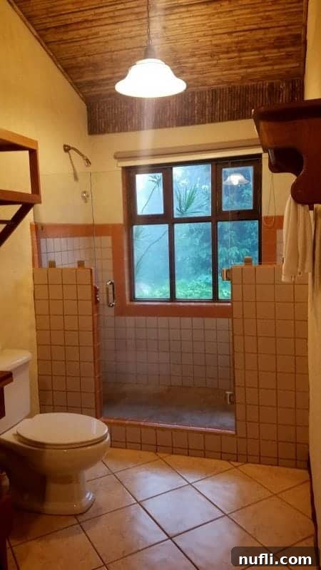 A spacious shower area within a casita, offering breathtaking views of the dense jungle through large windows, creating an immersive experience.