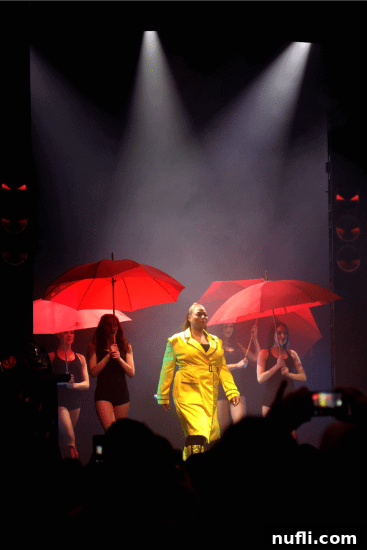 Queen Latifah on stage surrounded by lively dancers holding red umbrellas during her 'It's Raining Men' Lip Sync Battle performance
