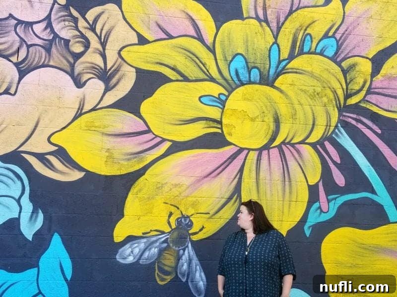 Woman standing by a vibrant bee and flower mural