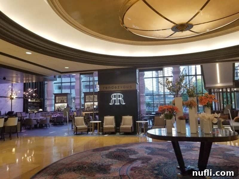 Rendezvous lounge sign amidst a beautiful floral arrangement in a vibrant hotel lobby, signaling a stylish meeting point