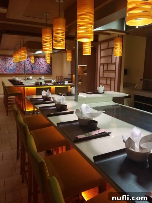 A vibrant scene at the Teppanyaki Grill on the Carnival Horizon, with chefs entertaining guests around a hot grill as they cook.