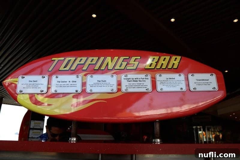 The vibrant toppings bar at Guy's Burger Joint, with a surfboard-themed sign, inviting guests to customize their delicious burgers.