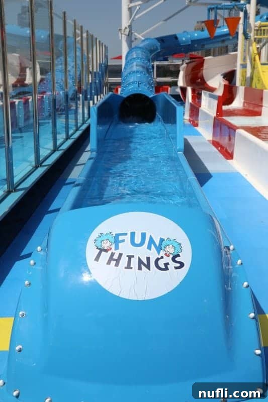 The 'Fun Things' sign marking the end of a blue waterslide, inviting children to enjoy a splashy finish.
