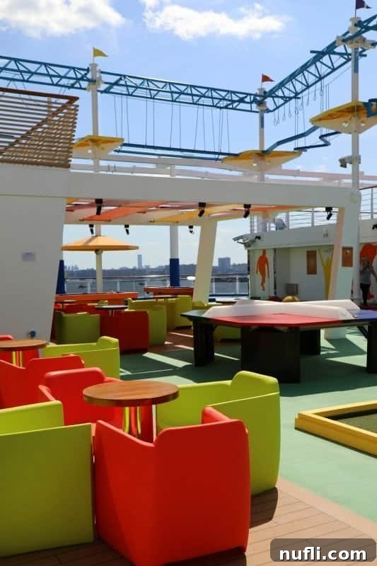 Tables and chairs set up for relaxation and games under a thrilling obstacle course structure on the Carnival Horizon's SportSquare.