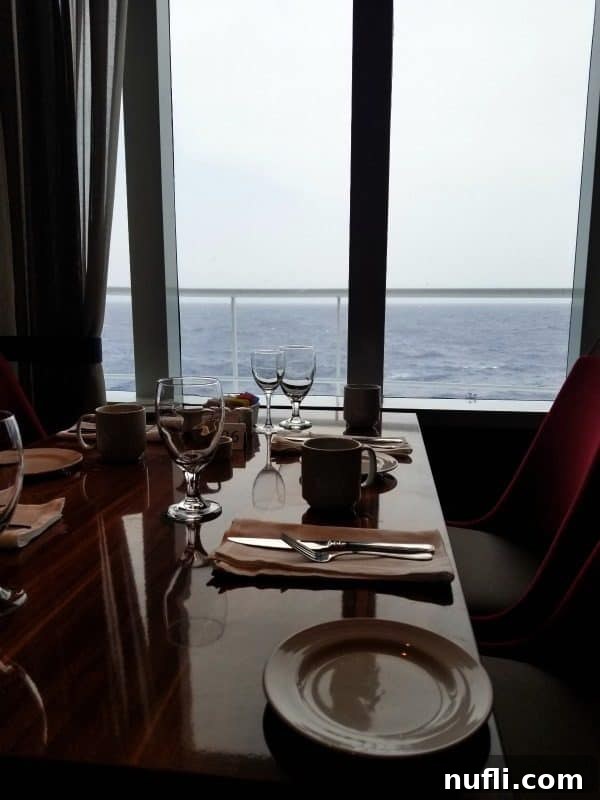 An elegant dining table with exquisite place settings, offering expansive ocean views from the Carnival Horizon main dining room.