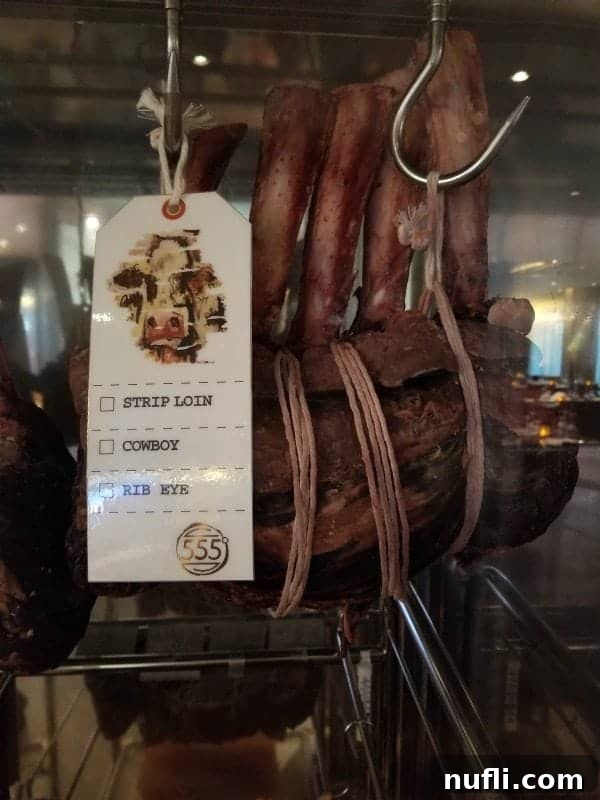 Artfully displayed meats, likely aging for optimal flavor, near the Fahrenheit 555 Steakhouse sign, emphasizing its quality offerings.