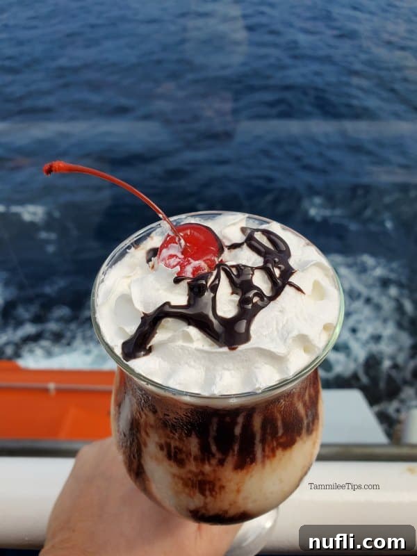 Decadent Mocha Retreat Cocktail 4 A refreshing Mocha Chocolate Getaway Cocktail served in an elegant hurricane glass, held by a hand, with the deep blue sea sparkling in the background.