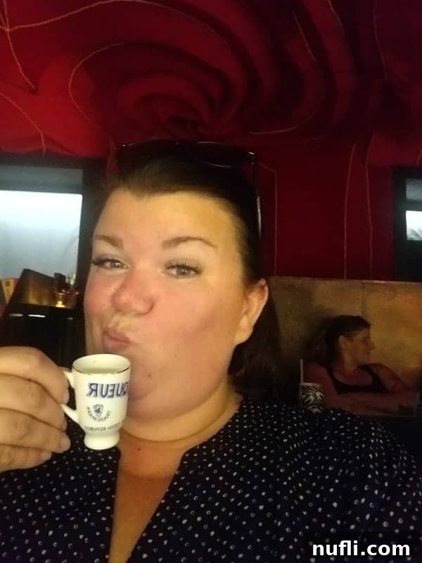 Tammilee holding a small glass of traditional Czech liqueur at a bar