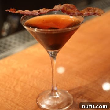 Smoky Bacon Manhattan 11 Bacon Manhattan in a martini glass with a slice of bacon for garnish